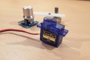 The SG90 micro servo motor. In the background is a rotary angle sensor module and a potentiometer. Both can be used to control the servo motor.